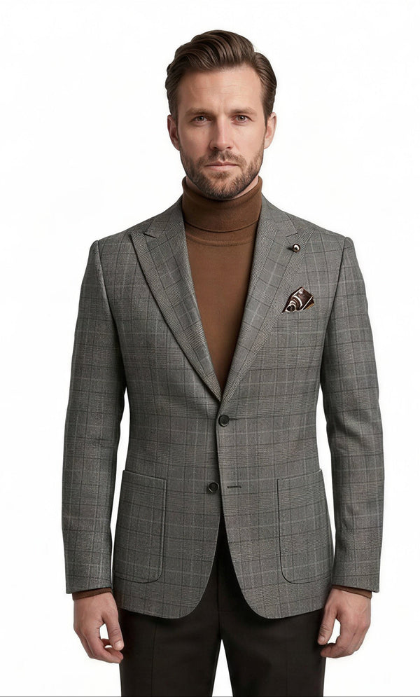 A man modeling a grey plaid suit jacket over a brown turtleneck sweater, paired with dark trousers and brown dress shoes, on a solid white background.