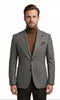 A man modeling a grey plaid suit jacket over a brown turtleneck sweater, paired with dark trousers and brown dress shoes, on a solid white background.